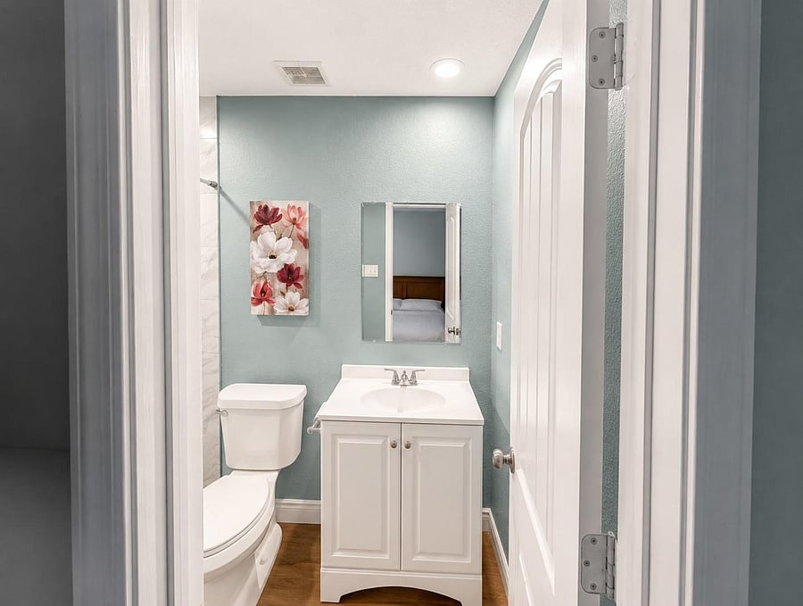 Full bathroom with a single-sink vanity, framed mirror, and a shower/tub combo, finished with clean paint and updated fixture