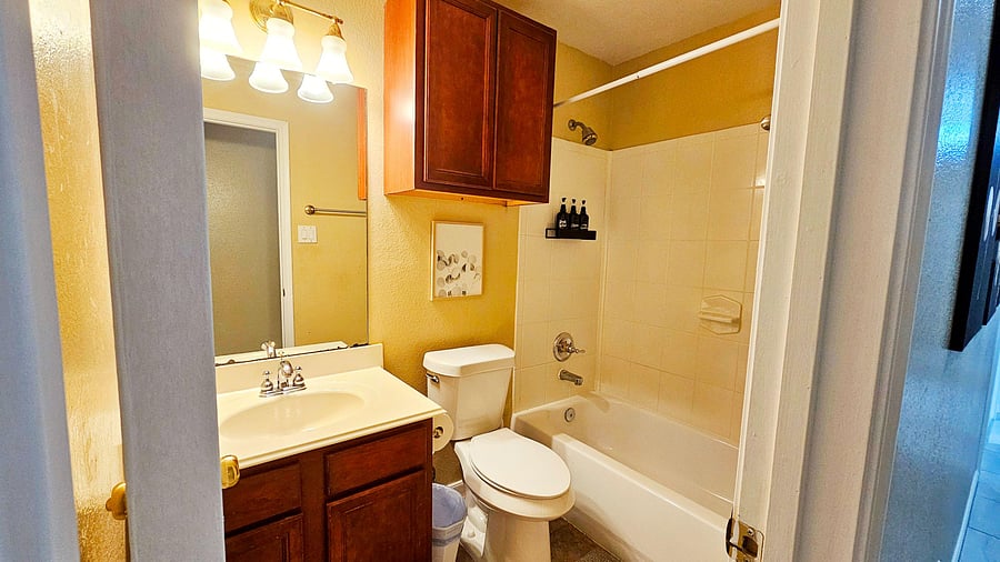 Full bathroom with tub/shower combo, tile surround, vanity with storage, and mirrored cabinet for daily essentials.