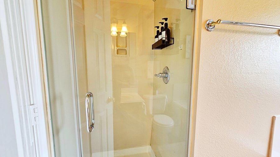 Glass-enclosed shower with built-in shelving and easy-clean surround, plus convenient towel bar storage nearby.