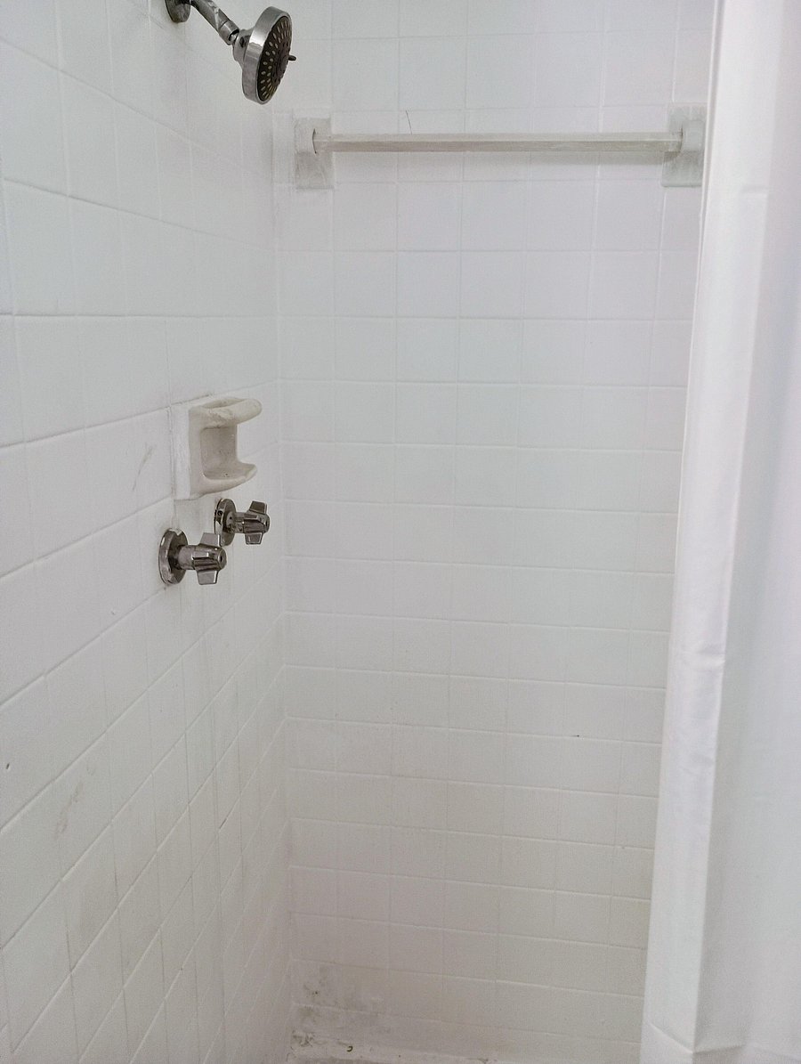 Tiled shower with adjustable showerhead, built-in soap dish, and a curtain rod for easy daily use.