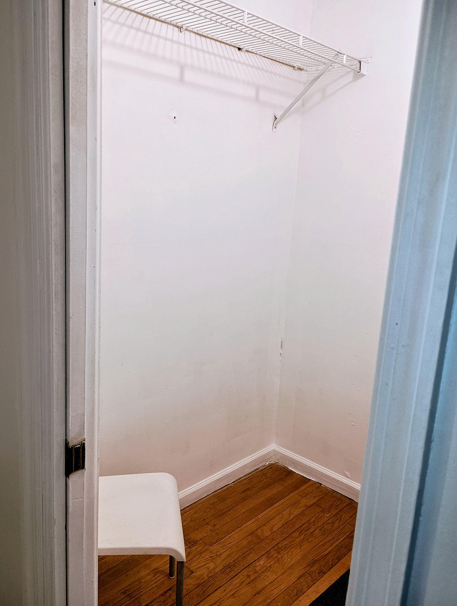 Walk-in closet with a ventilated wire shelf (left side) offering convenient storage space off the bedroom.