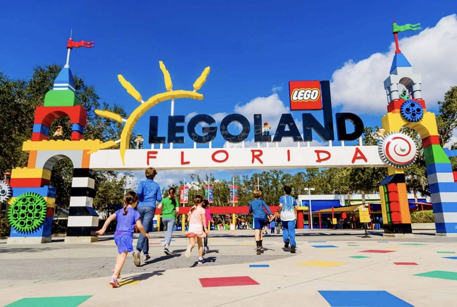 Outdoor public entrance plaza with colorful arch signage and wide paved walkways.