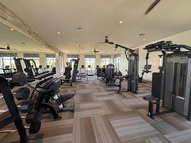 Spacious fitness room with cardio and strength equipment, mirrored wall, and ample floor space for workouts.