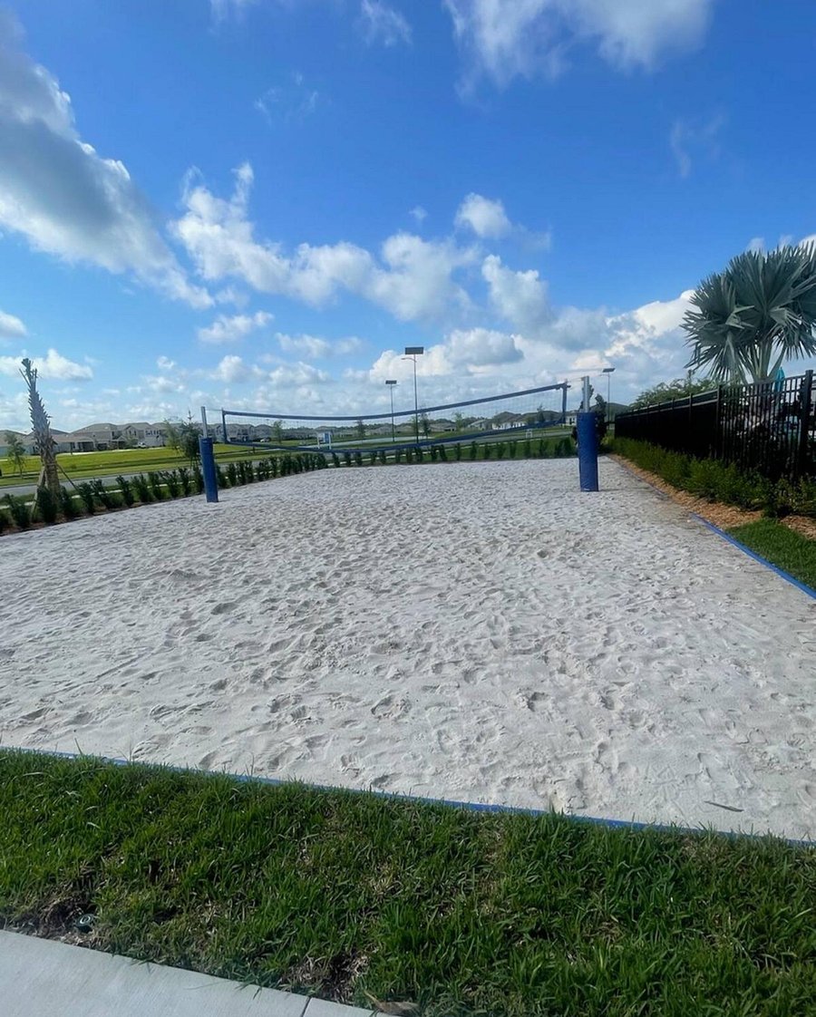 Community sand volleyball court with perimeter fencing and open green views, offering an easy spot for outdoor recreation.