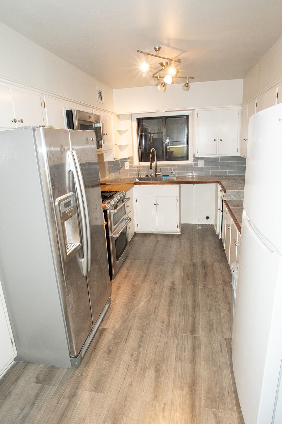 Full kitchen features plenty of cabinet space with a microwave, stove, oven, and two refrigerators.
