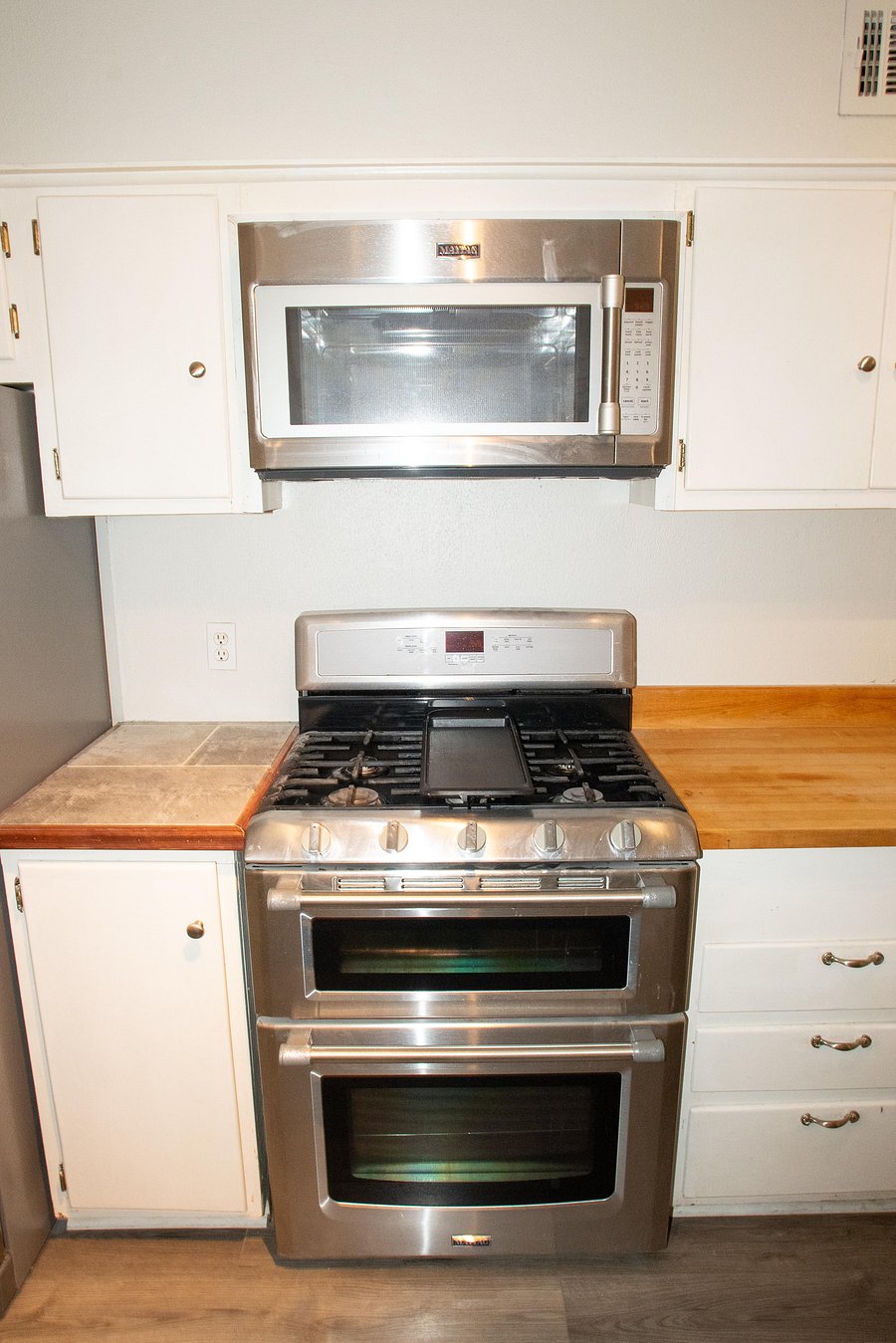 Full kitchen features plenty of cabinet space with a microwave, stove, oven, and two refrigerators.