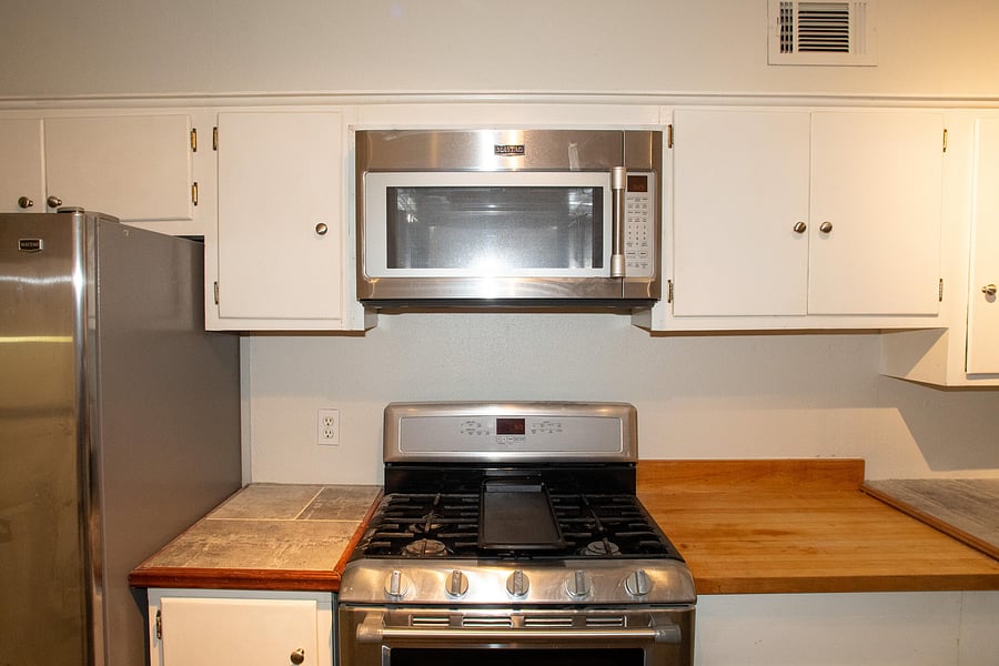 Full kitchen features plenty of cabinet space with a microwave, stove, oven, and two refrigerators.