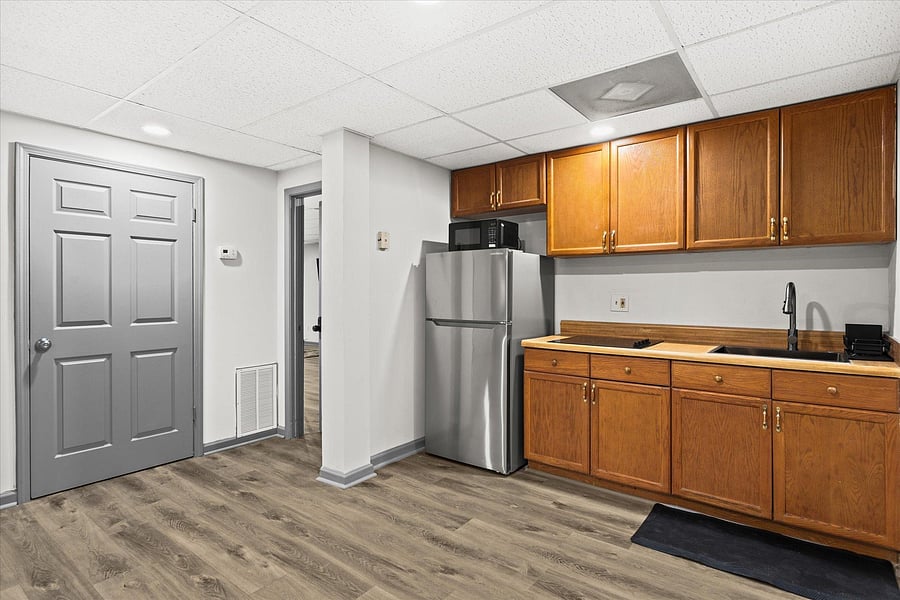 Basement kitchen equipped with electric stovetop, fridge, microwave, ands