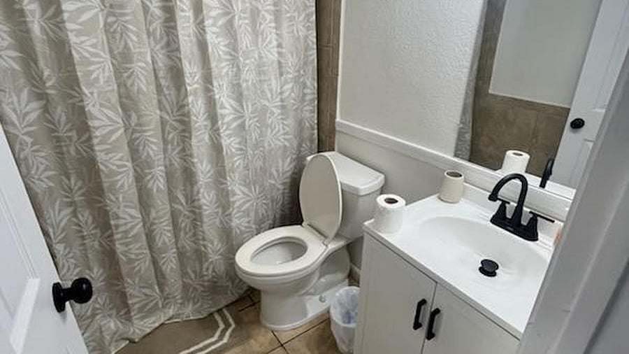 Full bathroom with tub/shower combo, updated vanity with storage, and a large mirror for everyday convenience.