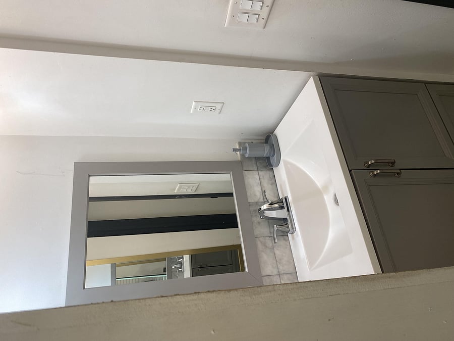 Bathroom vanity features a wide framed mirror, integrated sink, and under-cabinet storage for daily essentials.