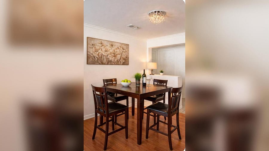 Dedicated dining area with a high-top table for four, hardwood-style floors, and an open pass-through to the kitchen.