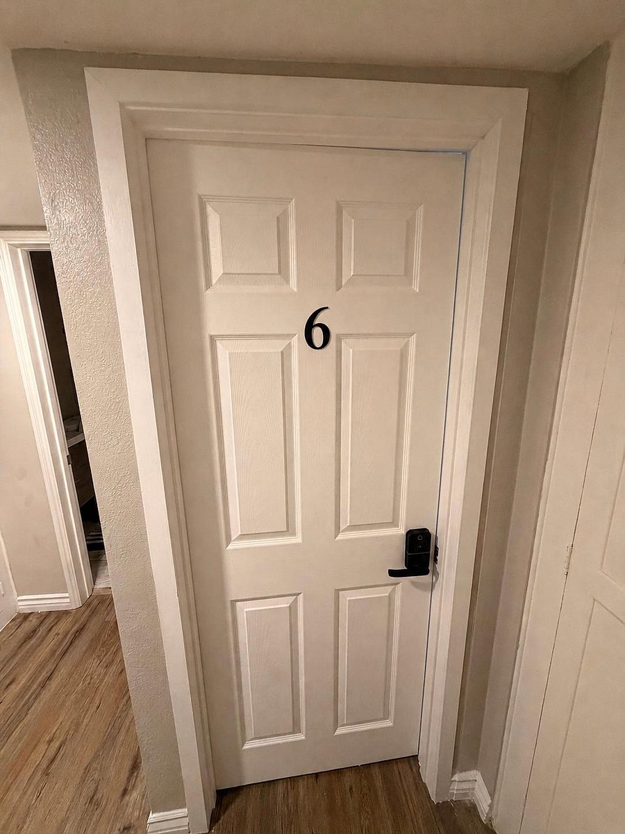 Interior hallway with durable wood-look flooring, neutral walls, and a numbered door with secure lever lock.