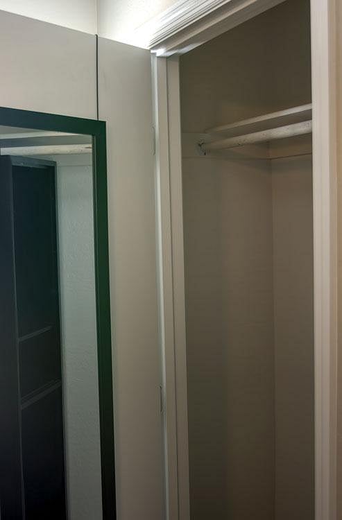Reach-in closet with hanging rod and upper shelf for convenient everyday storage.