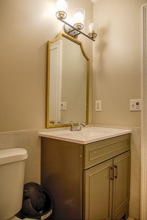 Bathroom vanity area with a single-sink cabinet, large framed mirror, and overhead light fixture for daily routines.