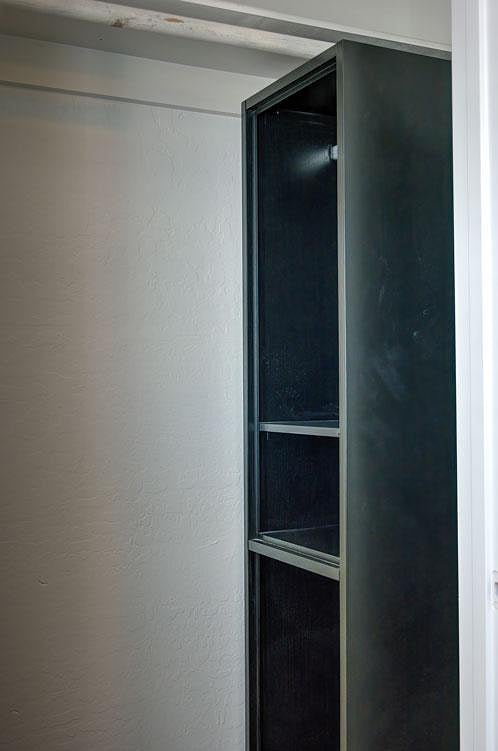 Built-in storage cabinet with open shelving provides convenient space for linens, supplies, or personal items.