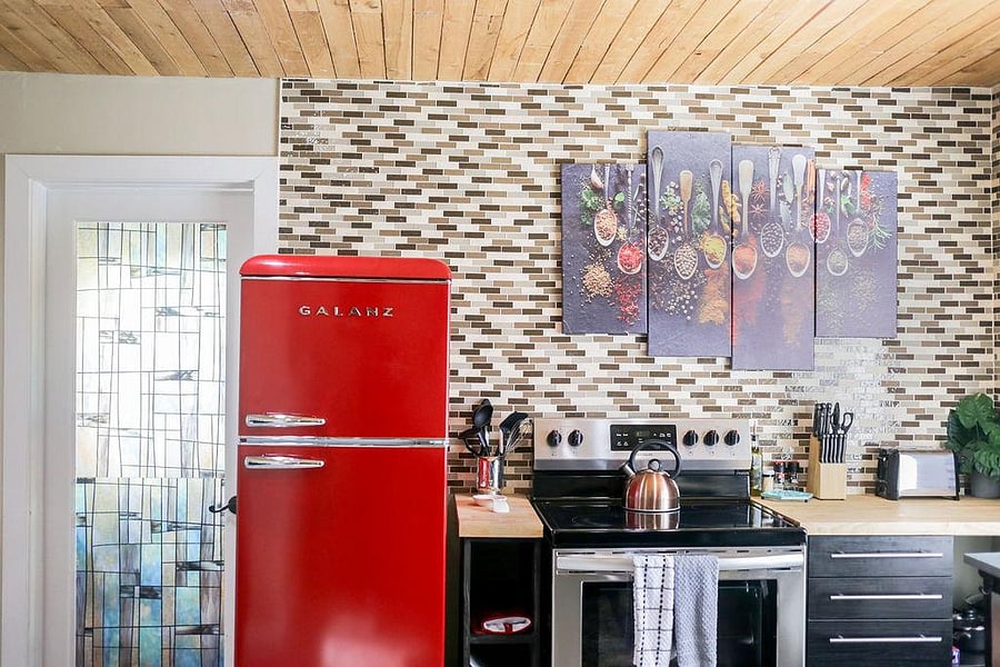 Bright and modern kitchen is shared with fridge, flat top stove, and cabinet space.