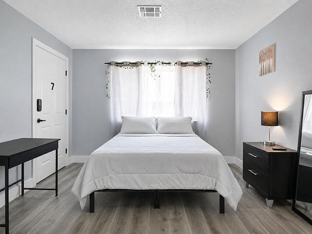 Well-appointed bedroom with a queen bed, nightstand lighting, and a large window with curtains for privacy and natural light.