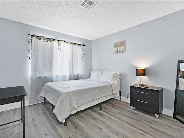 Spacious bedroom with a double bed, nightstand lighting, and a large window with curtains for privacy and natural light.