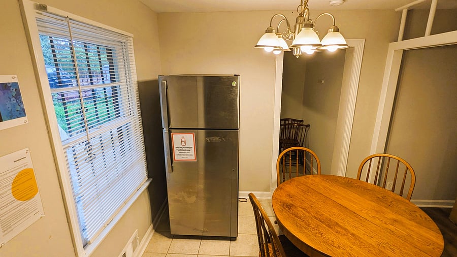 Dining area with a round table, overhead chandelier lighting, and a nearby refrigerator for convenient everyday meals.