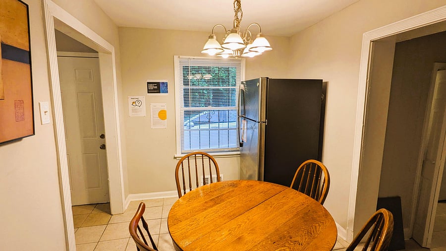Eat-in dining area with a round table, overhead chandelier, and nearby refrigerator for convenient everyday meals.