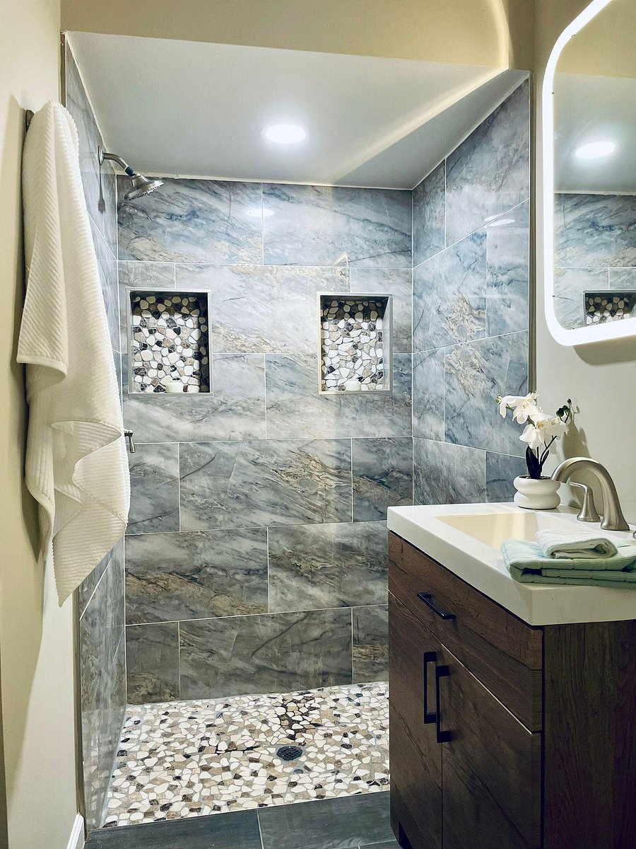 Updated walk-in shower with full tile surround and built-in niches, plus a vanity with ample drawer storage.