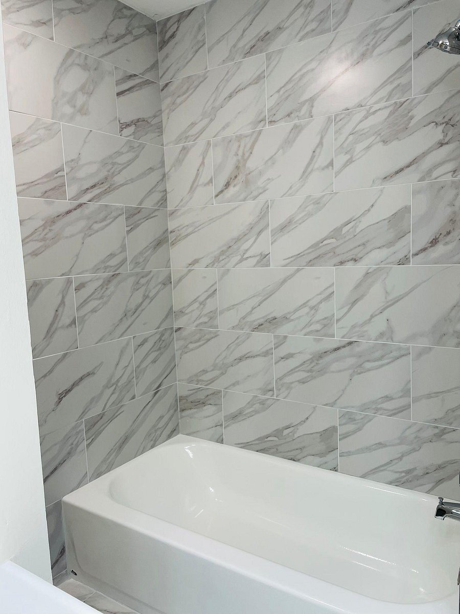 Tub/shower combo with oversized marble-look tile surround and clean, easy-care finishes.