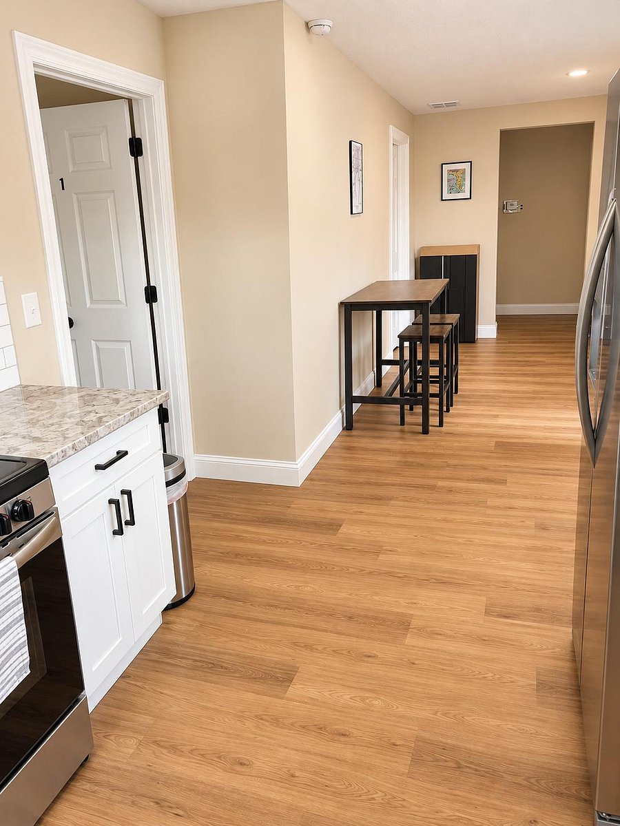 Eat-in kitchen area with bar-height table seating, wood-look flooring, and stainless-steel appliances nearby.