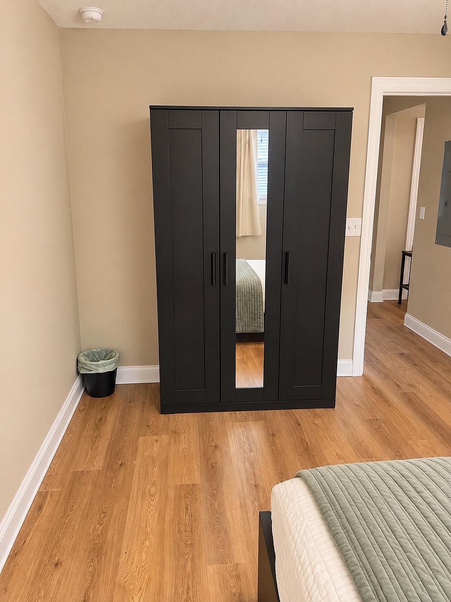 Bedroom with wood-style flooring and a large wardrobe featuring a full-length mirror for convenient storage and dressing.