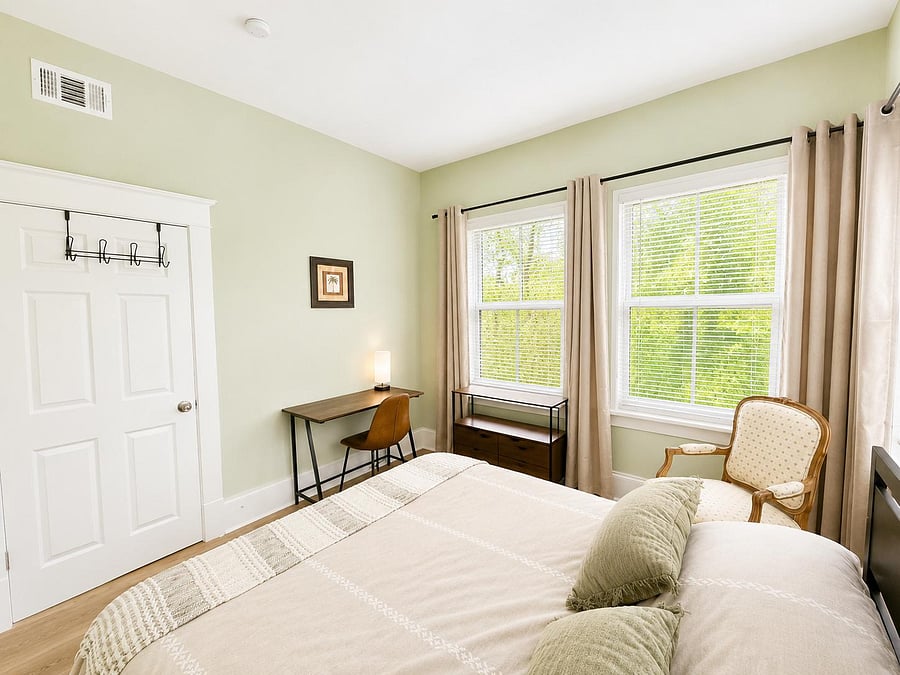 Well-appointed bedroom with two large windows, a dedicated desk workspace, and a closet for convenient storage.