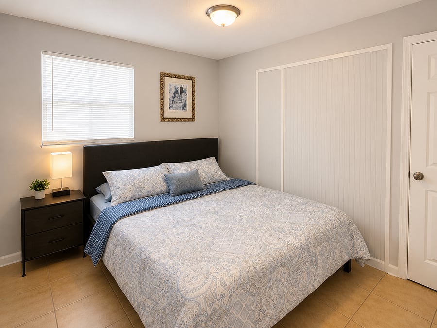 Well-appointed bedroom with a full-size bed, nightstand lighting, window blinds, and a spacious sliding-door closet.