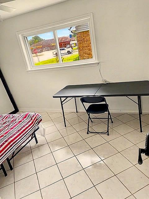 Private bedroom with tile flooring, a wide window for natural light, and space for a desk or study area.