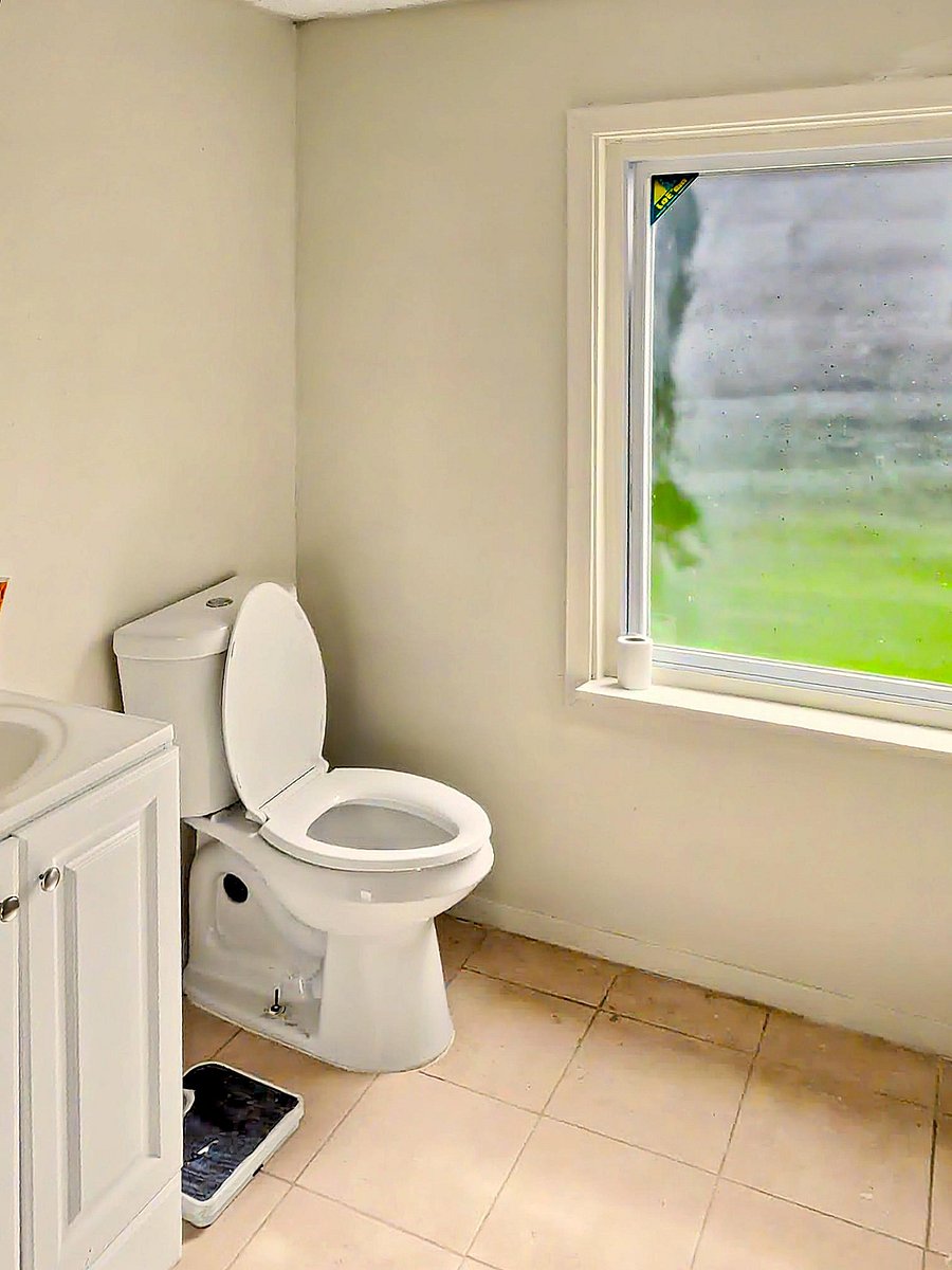 Bathroom with vanity storage, tile flooring, and a large window for natural light and ventilation.