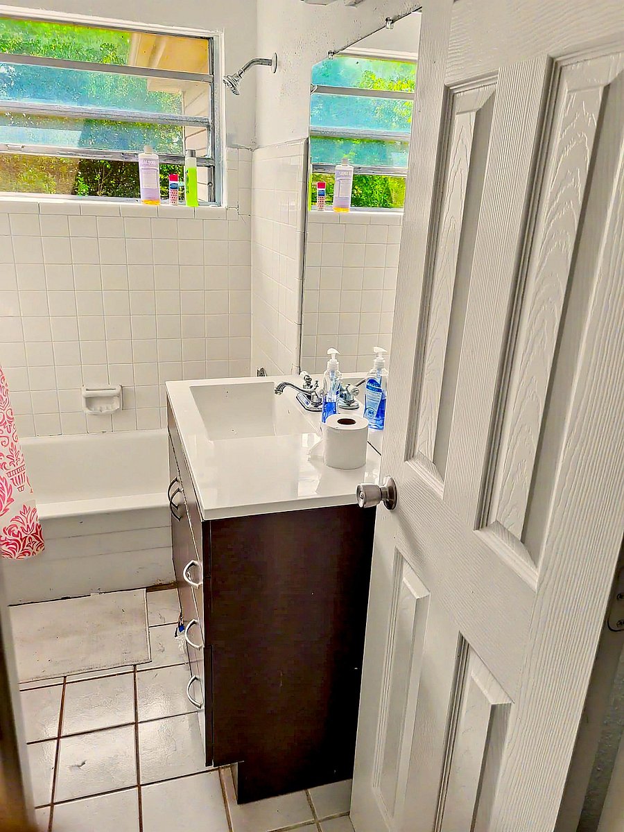 Full bathroom with a tub/shower combo, tile surround, and a vanity with sink plus a window for ventilation.