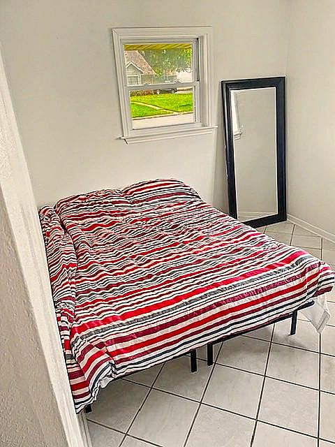 Private bedroom with a window for natural light, tiled flooring, and space for a full bed and personal furnishings.