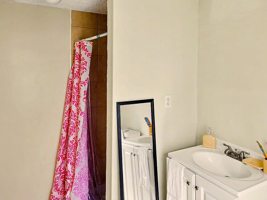 Full bathroom with a tub/shower combo, vanity sink with storage, and wall mirror for daily routines.