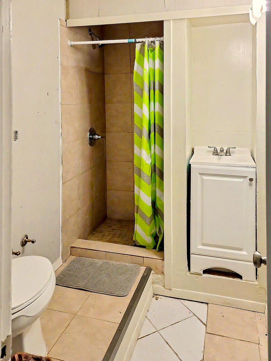 Compact bathroom with a tiled walk-in shower, curtain rod, and a vanity sink for everyday convenience.