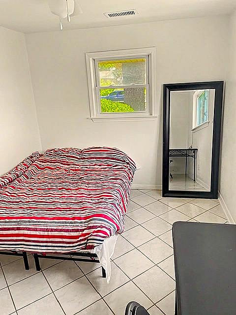 Private bedroom with tile flooring, a window for natural light, and space for a full bed plus additional furnishings.