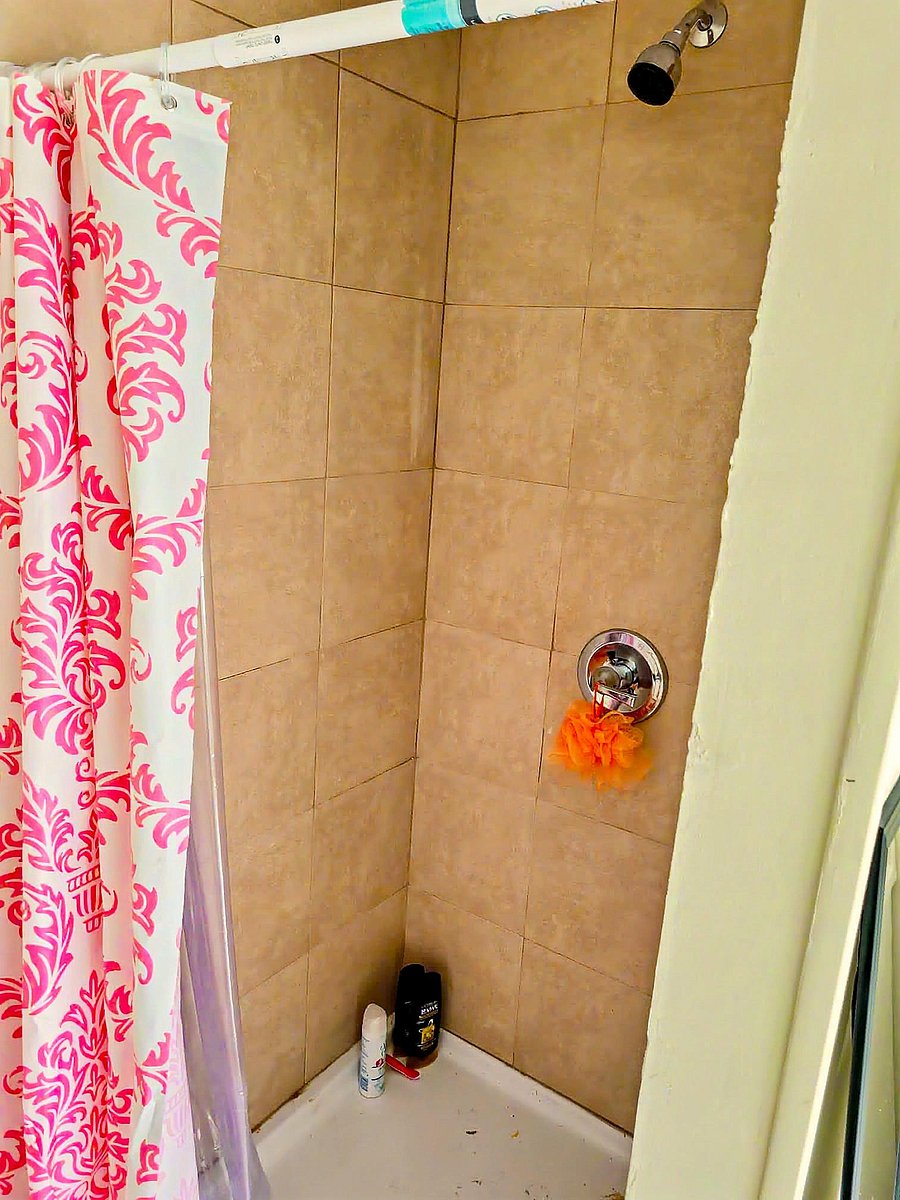 Tiled shower/tub combo with a curtain rod and wall-mounted showerhead for convenient everyday use.