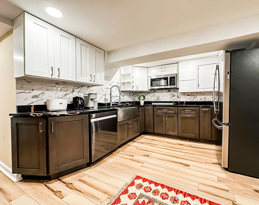 Updated U-shaped kitchen with ample cabinetry, stone-look counters, tile backsplash, and stainless steel appliances.