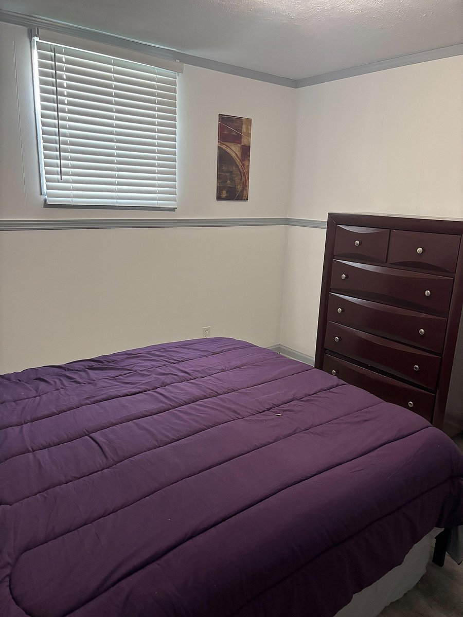 Bedroom with a window and blinds, comfortable bed setup, and a tall dresser for convenient in-room storage.
