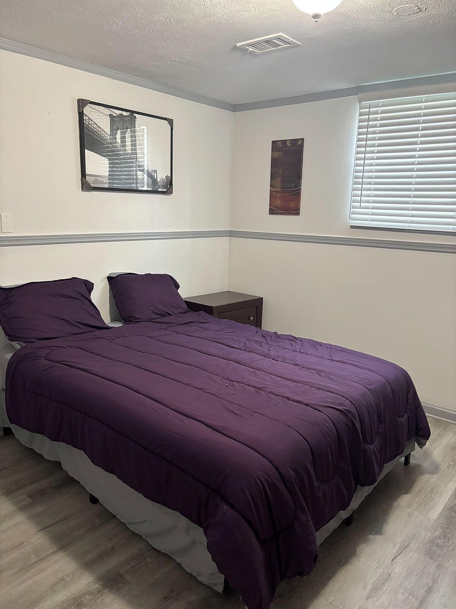 Furnished bedroom with a full bed, nightstand, and window blinds, plus durable flooring for easy upkeep.