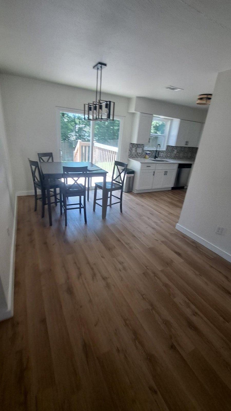 Open dining area flows into the kitchen and opens to a deck through sliding glass doors, offering easy indoor-outdoor living.