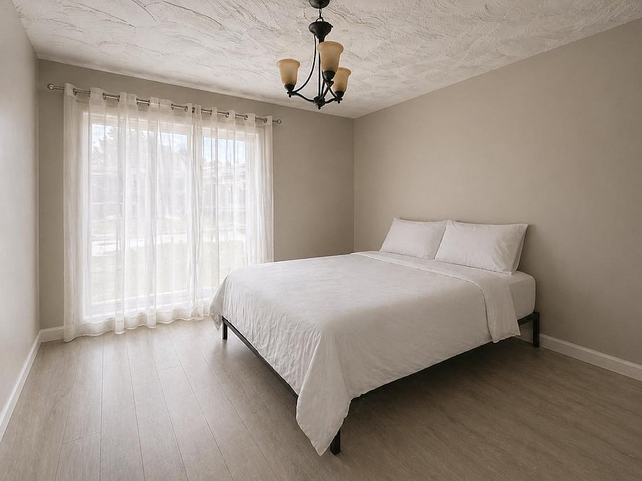 Spacious bedroom with large window, soft window treatments, and durable flooring--ideal for restful nights and easy upkeep.