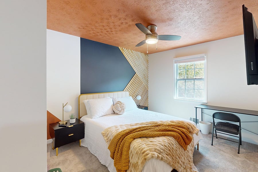 This Queen bedroom is equipped with a ceiling fan, work desk and a chair, luxurious mattress, lamps, side tables and a closet