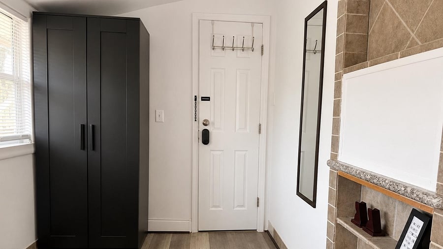 Functional entryway with a secure front door, wall hooks, and a freestanding wardrobe for easy organization.