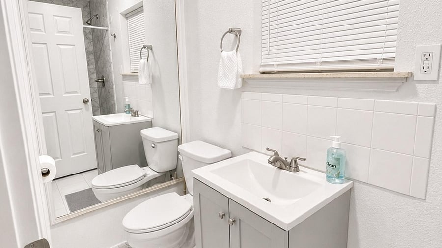 Updated bathroom with a sleek vanity, tile flooring, and a walk-in shower with marble-look surround and curtain.