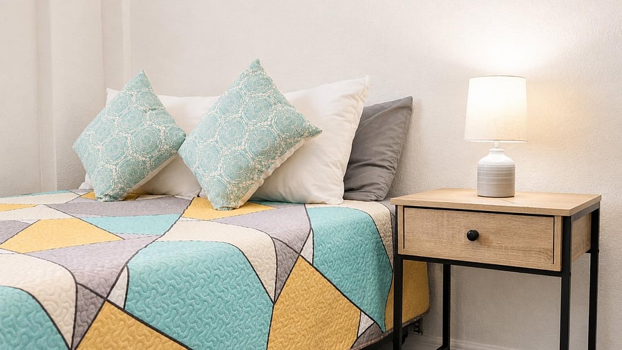 Neatly furnished bedroom setup with a comfortable be,  a nightstand with lamp for convenient bedside lighting,
