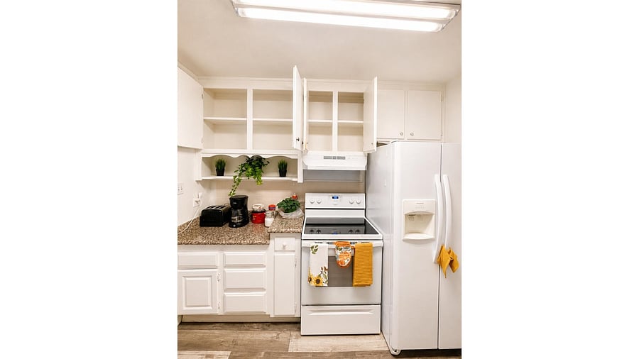 Efficient kitchen with generous cabinetry, stone counters, electric range, and side-by-side fridge.