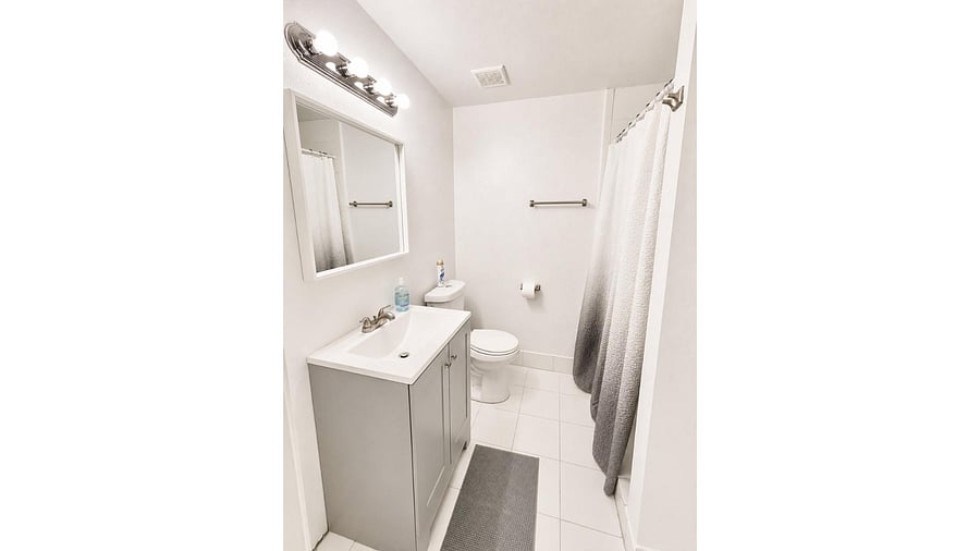 Clean full bathroom featuring a single-sink vanity with storage, large mirror, and a shower with curtain.
