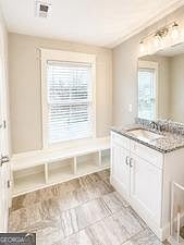 Well-appointed bathroom with a wide vanity, stone-look counters, large mirror, and a window for natural light.